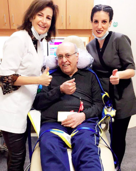 Dr. Natalie Archer and dental hygienist beside a geriatric dental patient in a wheelchair.