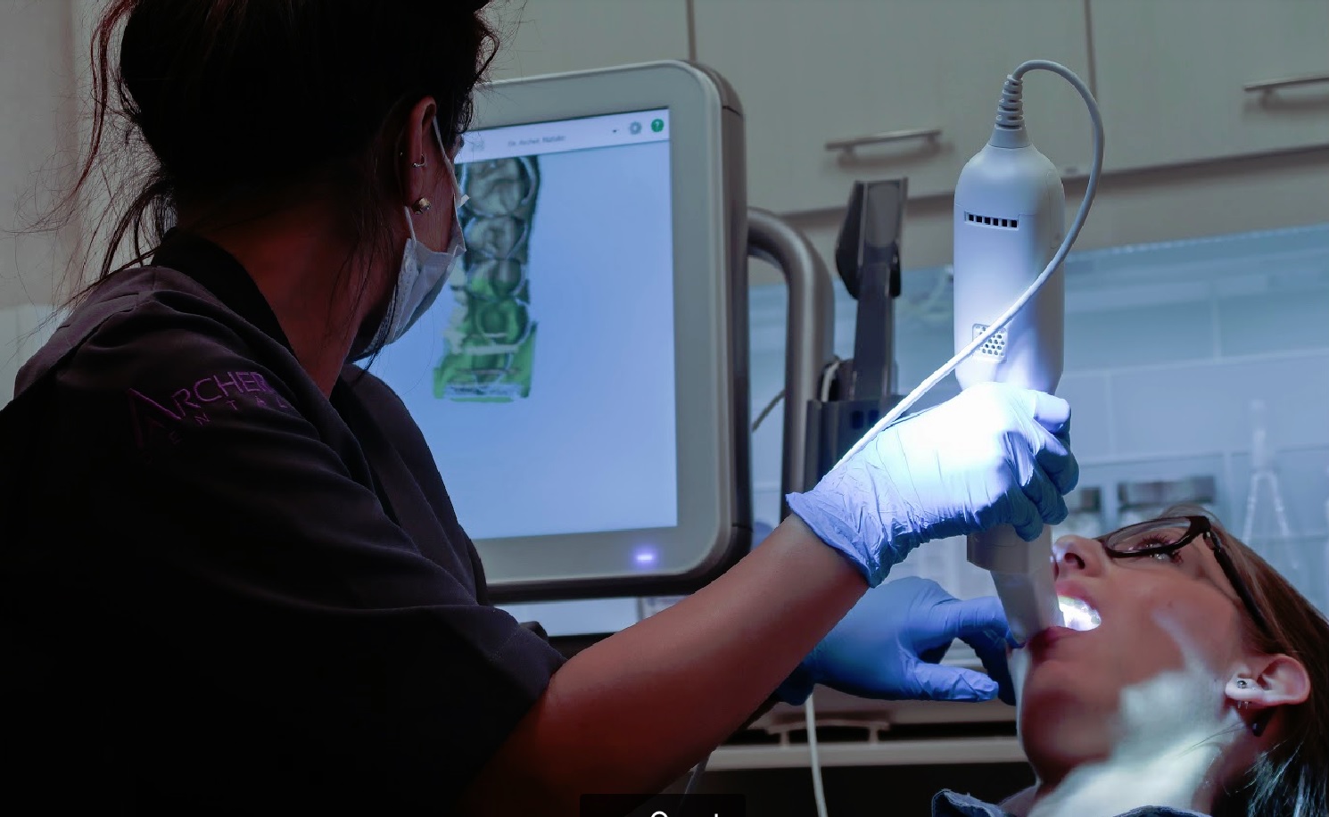 Dental assistant uses i-teroscanner to to scan teeth alignment, occlusion (bite) before using computer processer to plot correct/alignment.